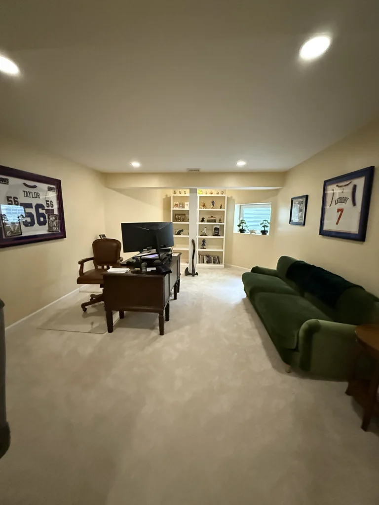 A fully finished basement converted into a spacious home office with plush carpeting and recessed lighting.