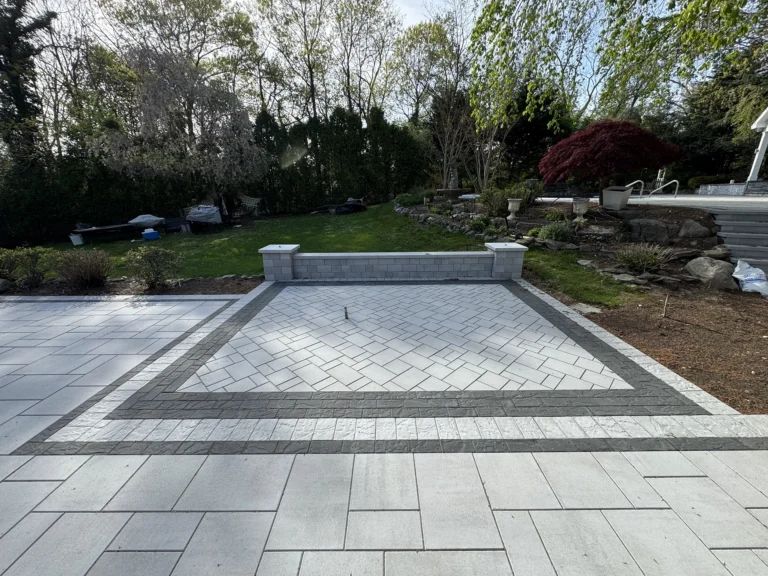 Backyard patio featuring a double-bordered inlay with a herringbone paver pattern in the center.