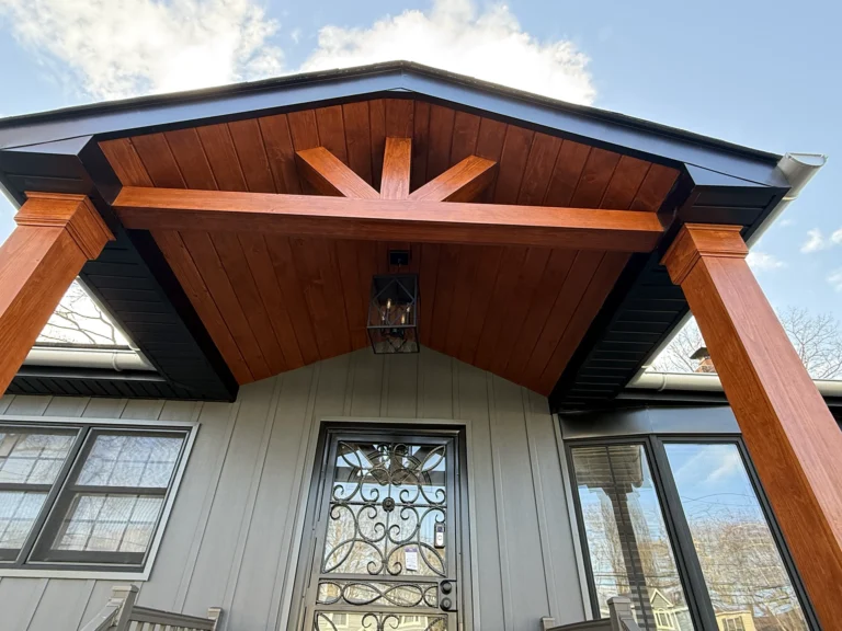 Detail view of a front porch ceiling featuring rich wood beams and a cedar tongue-and-groove finish.