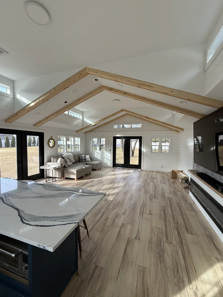 Large living area with shiplap walls, exposed wood rafters, and light oak wood-look flooring.