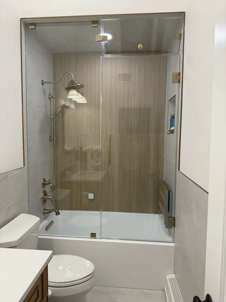 Bathroom remodel featuring vertical wood-look tile accents and brushed bronze fixtures.